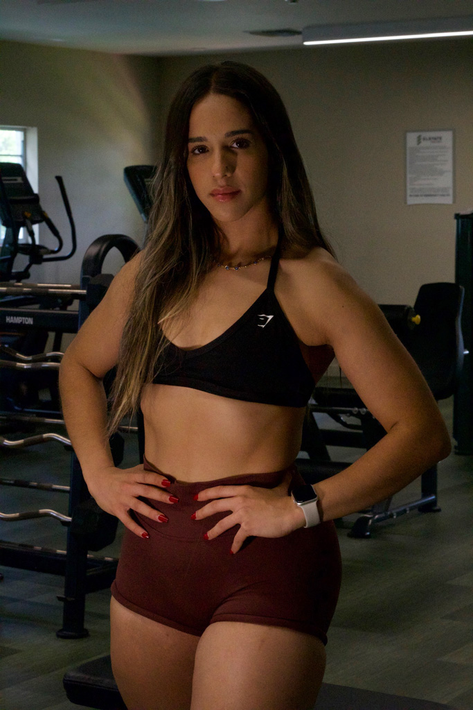 La entrenadora posa con confianza en el gimnasio.